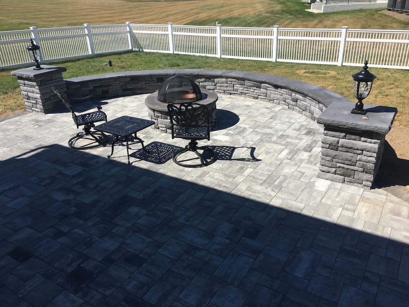 custom patio with seat wall and fire pit - gray natural stone with black cap stones and lighting