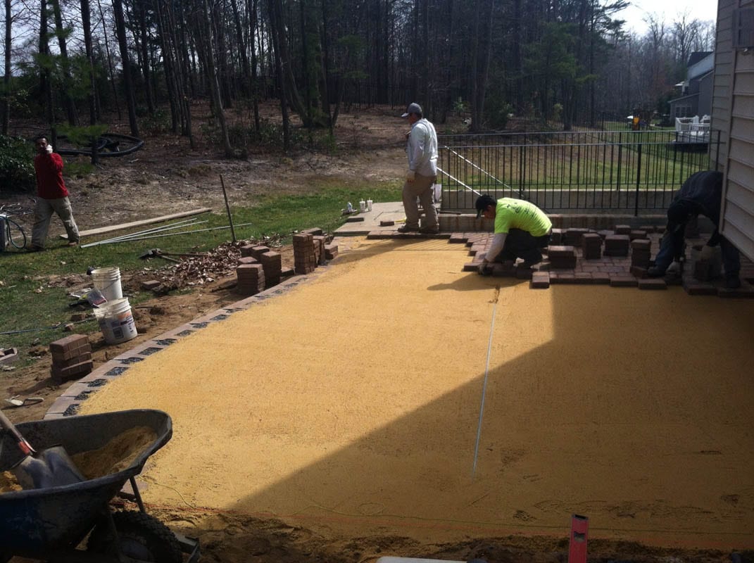 Placing pavers during patio construction behind home