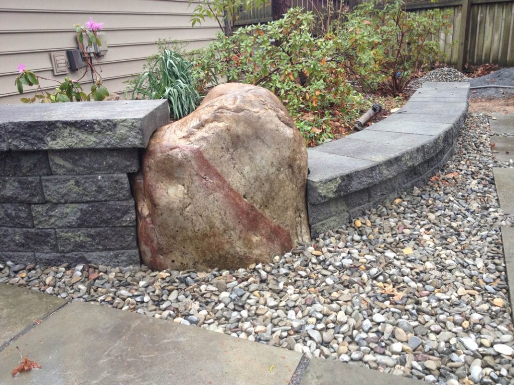 Wall constructed adjacent to a natural landscape stone