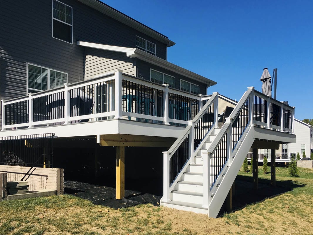Newly built white composite deck with stairway on rear of home
