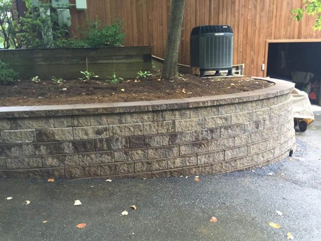Retaining wall constructed adjacent to landscape flower beds and driveway